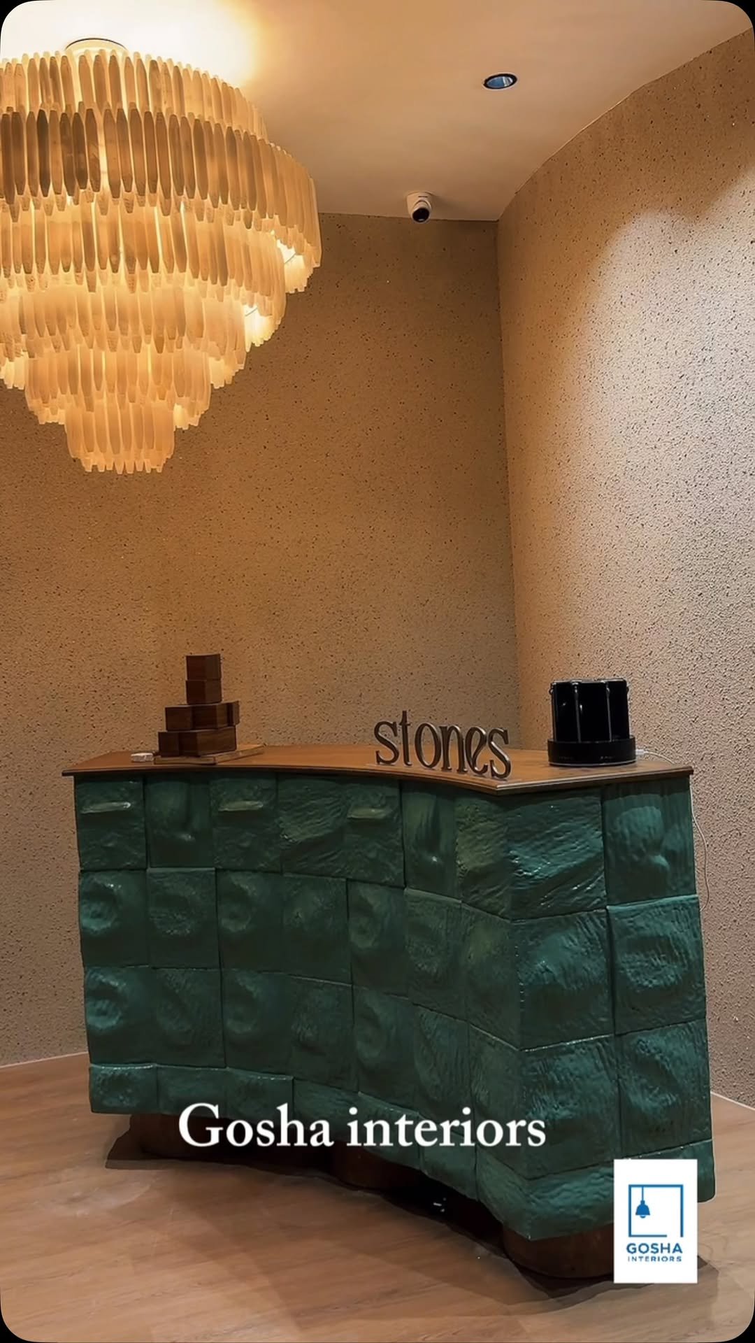 Gosha fit-out at Stones Spa: textured green stone reception beneath a sculptural chandelier